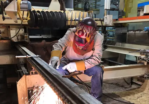J Gant Construction worker cutting a steel beam in the fabrication shop